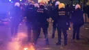 Petugas polisi Belgia berjalan di samping api di jalan selama bentrokan setelah timnas Maroko pada laga semifinal Piala Dunia 2022, di Brussel, Rabu (14/12/2022). Para suporter itu melemparkan kembang api di dekat stasiun Brussel Selatan setelah Maroko kalah 0-2 dari Prancis. (Simon Wohlfahrt / AFP)