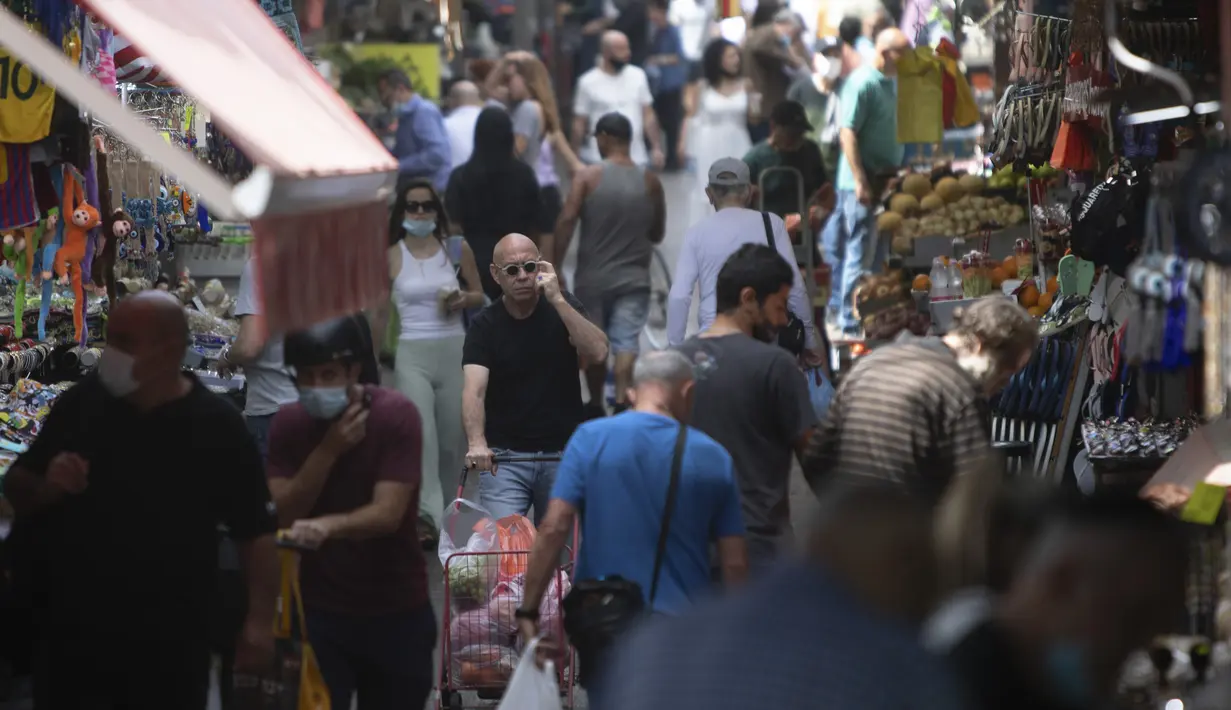 Orang Israel berjalan di pasar yang sibuk di Tel Aviv, Minggu (18/4/2021). Israel mencabut aturan wajib masker di ruang publik luar ruangan dan membuka kembali sekolah sepenuhnya dalam upaya menuju normalisasi setelah kampanye vaksinasi Covid-19 berjalan sukses. (AP Photo/Sebastian Scheiner)