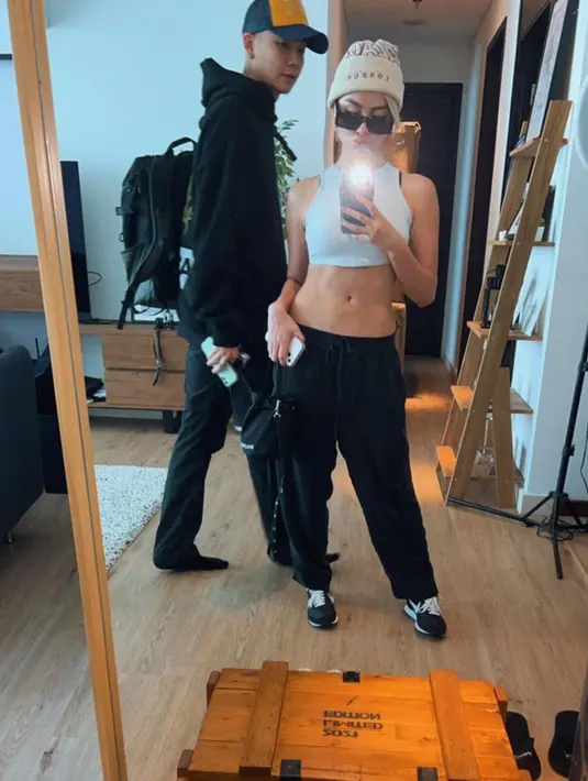 Mirror selfie bersama sang kekasih, Agnez Mo memamerkan body goalsnya. Ia tampak mengenakan cropped top putih, dipadu dengan jogger pants hitam, bucket hat putih gading, dan sunglasses. [Foto: Instagram/agnezmo]