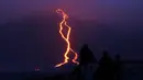 Warga melihat guguran lava pijar yang keluar dari gunung api Piton de la Fournaise atau Peak of the Furnace di Pulau Reunion, Samudera Hindia, Prancis, Selasa (13/8/2019). Letusan Piton de la Fournaise berlanjut hingga hari ketiga. (Richard BOUHET/AFP)