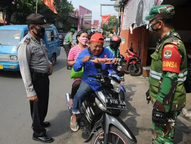 Anggota TNI-Polri menghentikan warga yang tidak mengenakan masker saat razia gabungan Kelurahan Gandul di Perempatan Gandul, Cinere, Depok, Kamis ( 29/08/2020). Razia ditujukan untuk menekan penyebaran Covid-19 dengan memberikan sanksi berupa hukuman fisik dan kerja sosial. (merdeka.com/Arie Basuki)