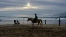 Seorang wisatawan menunggangi kuda saat berlibur Lebaran di Pantai Lhoknga, Aceh Besar, Aceh, Minggu (9/6/2019). (CHAIDEER MAHYUDDIN/AFP)