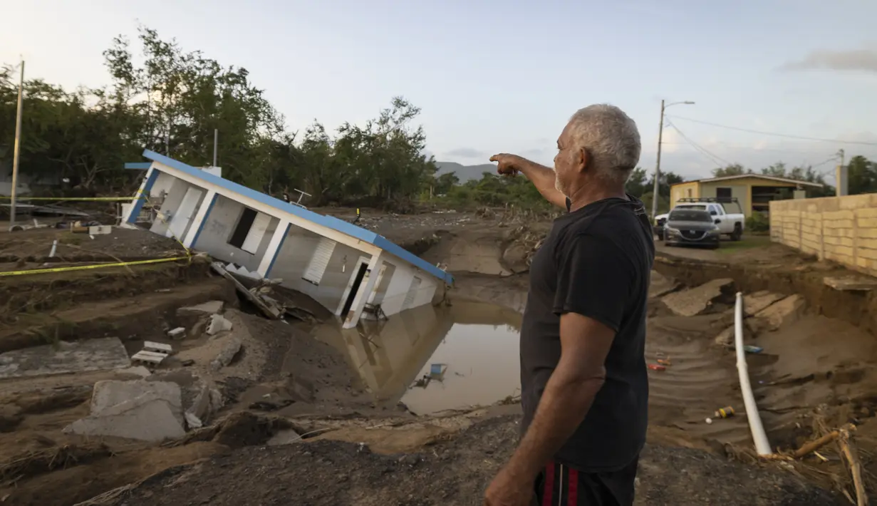 Seorang pria menunjuk ke sebuah rumah yang runtuh akibat Badai Fiona di Villa Esperanza di Salinas, Puerto Rico, Rabu, 21 September 2022. (AP Photo/Alejandro Granadillo)