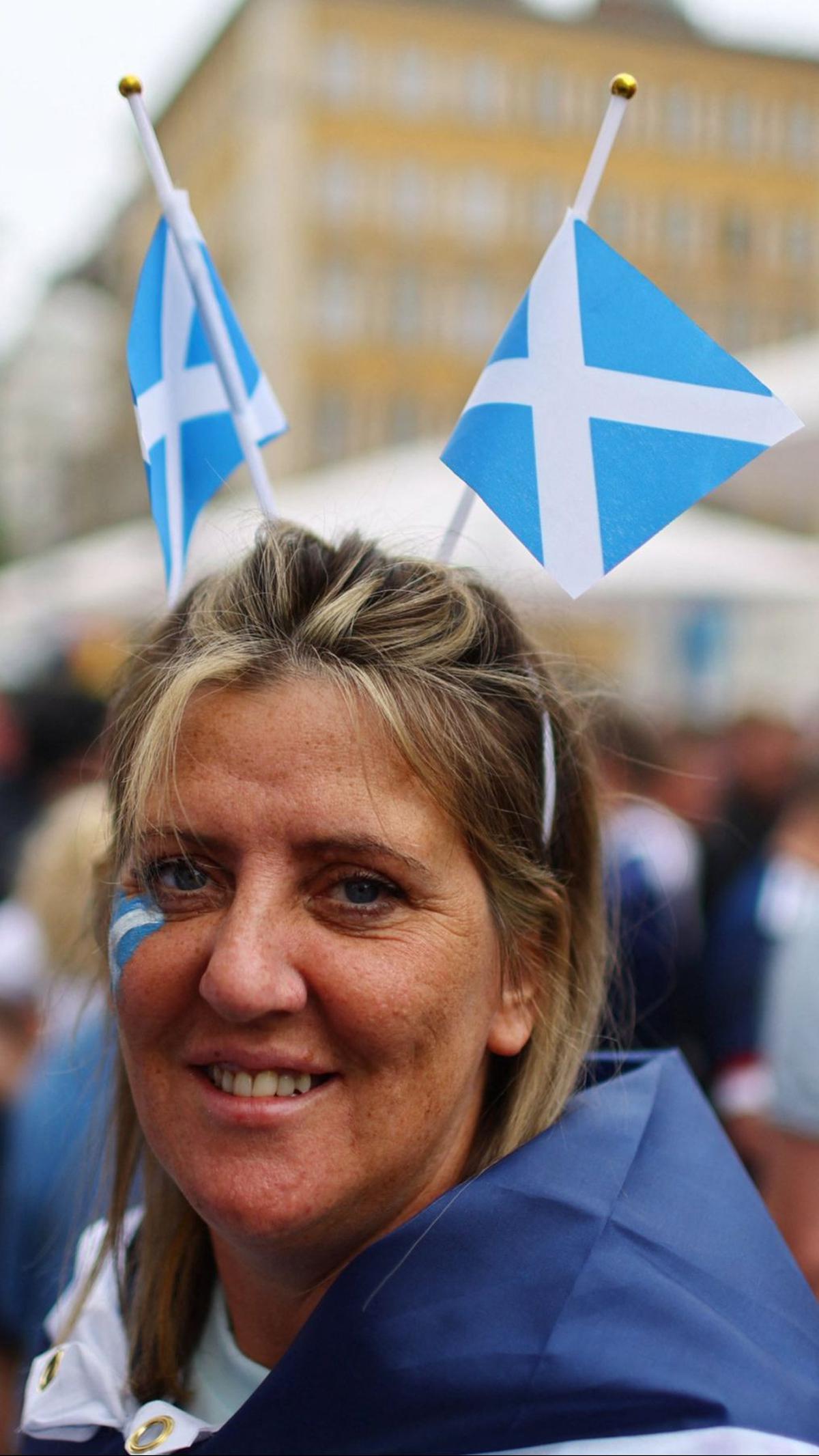 Seorang wanita tampil dengan atribut bendera Skotlandia di kepala dan wajahnya.&nbsp;Foto: REUTERS/Leonhard Simon