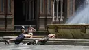 Dua pemuda membenamkan kepala mereka ke dalam air mancur untuk mendinginkan diri, di alun-alun Plaza de Espana di Seville, Spanyol pada 7 Agustus 2023. (CRISTINA QUICLER / AFP)