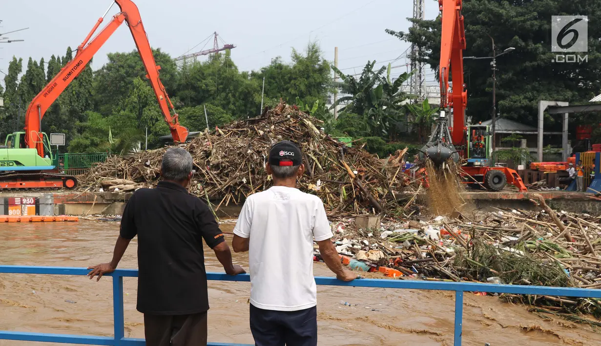 Warga melihat tumpukan sampah yang didominasi potongan bambu dan botol plastik menumpuk di Pintu Air Manggarai, Jakarta, Jumat (26/4). Sampah ini terbawa arus sungai Ciliwung akibat curah hujan yang tinggi di kawasan Bogor dan sekitarnya, Kamis (25/4). (Liputan6.com/Helmi Fithriansyah)
