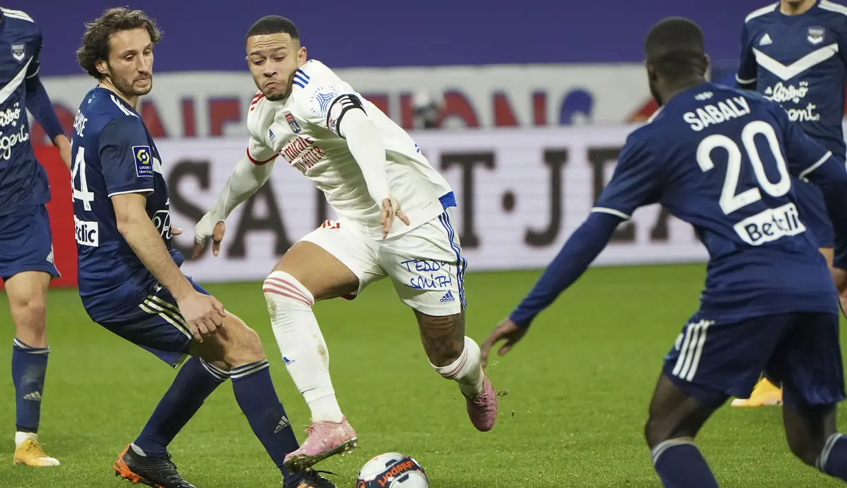 Striker Lyon, Memphis Depay menggiring bola di antara dua pemain Bordeaux, Vukasin Jovanovic (kiri) dan Youssouf Sabaly dalam laga lanjutan Liga Prancis 2020/21 pekan ke-22 di Groupama Stadium, Jumat (29/1/2021). Lyon menang 2-1 atas Bordeaux. (AP/Laurent Cipriani)