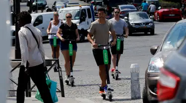 Orang-orang beraktivitas menggunakan skuter listrik di Paris, Prancis (9/7). Skuter listrik ini dibuat oleh perusahaan AS Lime yang merupakan penyewaan transportasi sepeda dan skuter di berbagai kota. (AFP Photo/Francois Guillot)