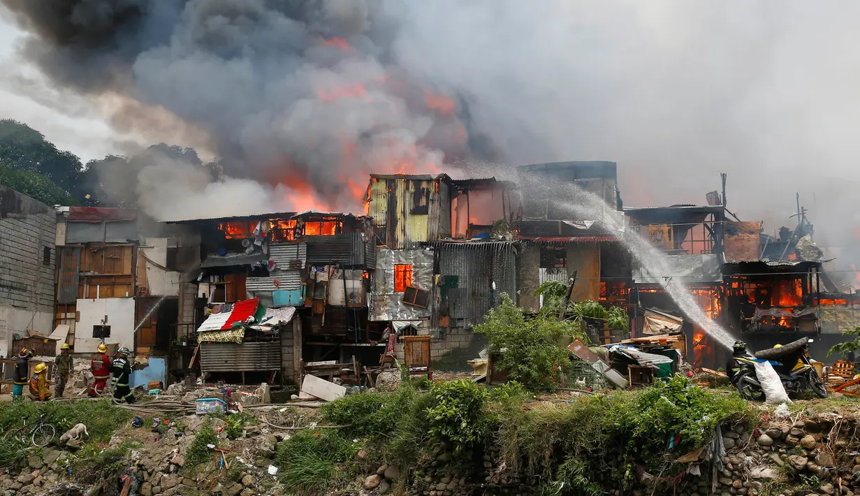 Petugas pemadam kebakaran berusaha memadamkan api yang membakar kawasan kumuh di Manila, Filipina (11/8). Api yang membakar pemukiman selama tiga jam tersebut menelan 300 rumah. (AP Photo/Bullit Marquez)