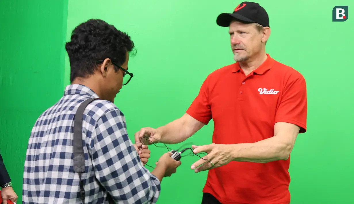 Wartawan Bola.com, Abdul Aziz, memberikan clip on saat wawancara eksklusif dengan kiper legendaris Manchester United, Peter Schmeichel, di SCTV Tower, Jakarta, Jumat (4/8/2023). (Bola.com/M Iqbal Ichsan)