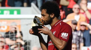 Mohamed Salah mencium penghargaan Sepatu Emas yang diraihnya setelah Liverpool menekuk Brighton and Hove Albion di Anfield, Minggu (13/5). Salah merebut Sepatu Emas atas keberhasilannya menjadi top scorer Premier League musim ini. (AFP/Paul ELLIS)
