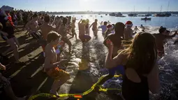 Orang-orang berlari menuju pantai untuk ambil bagian dari acara tahunan Polar Bear Swim di Vancouver, Kanada (2/1/2016). Meski suhu di pantai tersebut mencapai 3 derajat celcius, mereka tetap antusias. (REUTERS / Ben Nelms)