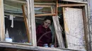Seorang perempuan berdiri di dekat jendela yang pecah di apartemennya setelah serangan bom Rusia di Kiev, Ukraina, Senin, 14 Maret 2022. Rusia melancarkan invasi berskala besar ke Ukraina, salah satu negara tetangganya di sebelah barat daya. (AP Photo/Efrem Lukatsky)