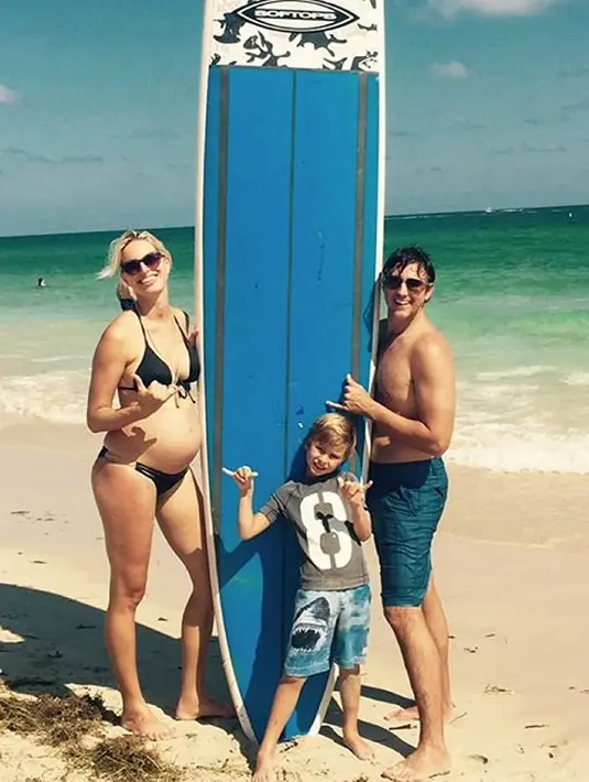 Karolina Kurkova bersama suami dan anaknya. Terlihat Karolina sedang berpose di pinggir pantai dengan perutnya yang membesar sambil memegang papan selancar. (Istimewa)