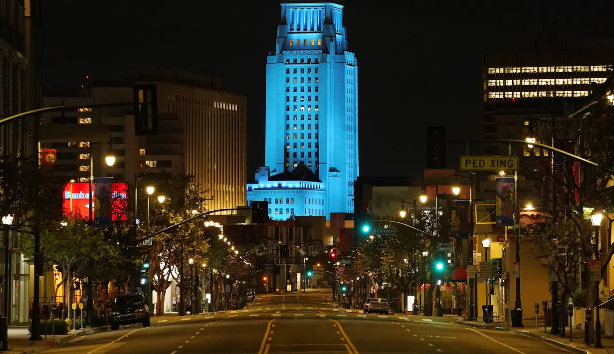 Balai Kota Los Angeles menyala biru saat Broadway terlihat sepi, Los Angeles, Amerika Serikat, Jumat (10/4/2020). Balai Kota dan beberapa landmark Los Angeles menyala biru untuk menunjukkan dukungan kepada petugas medis mengahadapi virus corona COVID-19. (AP Photo/Mark J. Terrill)