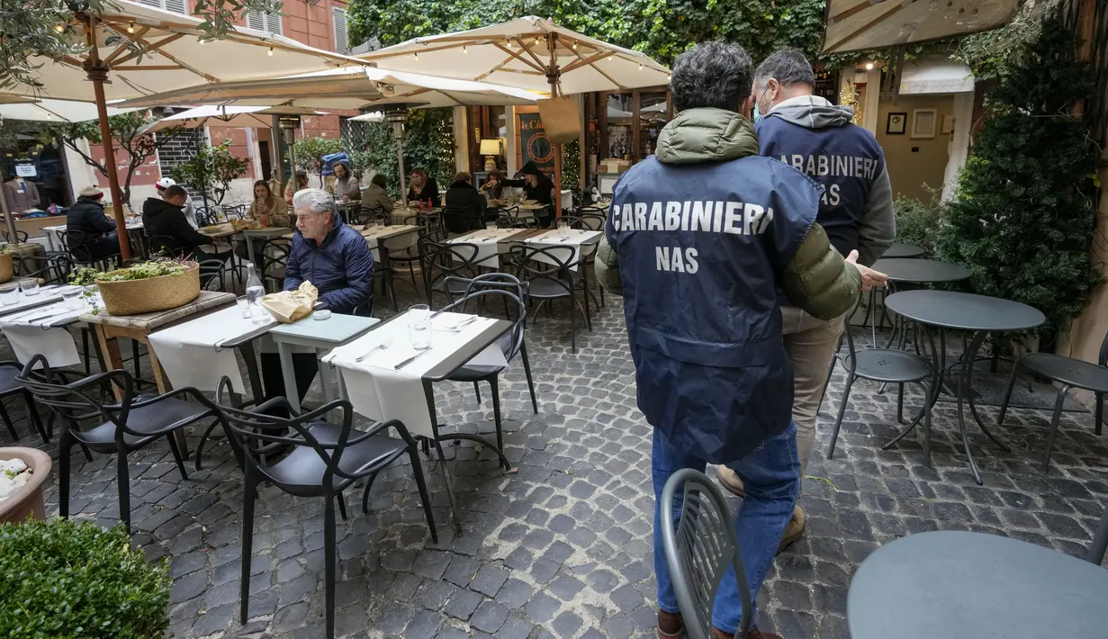 Polisi Carabinieri tiba untuk memeriksa kartu kesehatan Covid-19 pengunjung restoran saat pemberlakuan ‘Super Green Pass’ di Roma, Senin (6/12/2021). Polisi Italia dapat memeriksa apakah pengunjung memiliki Green Pass yang menunjukkan bukti vaksinasi atau kesembuhan dari virus. (AP/Andrew Medichini)