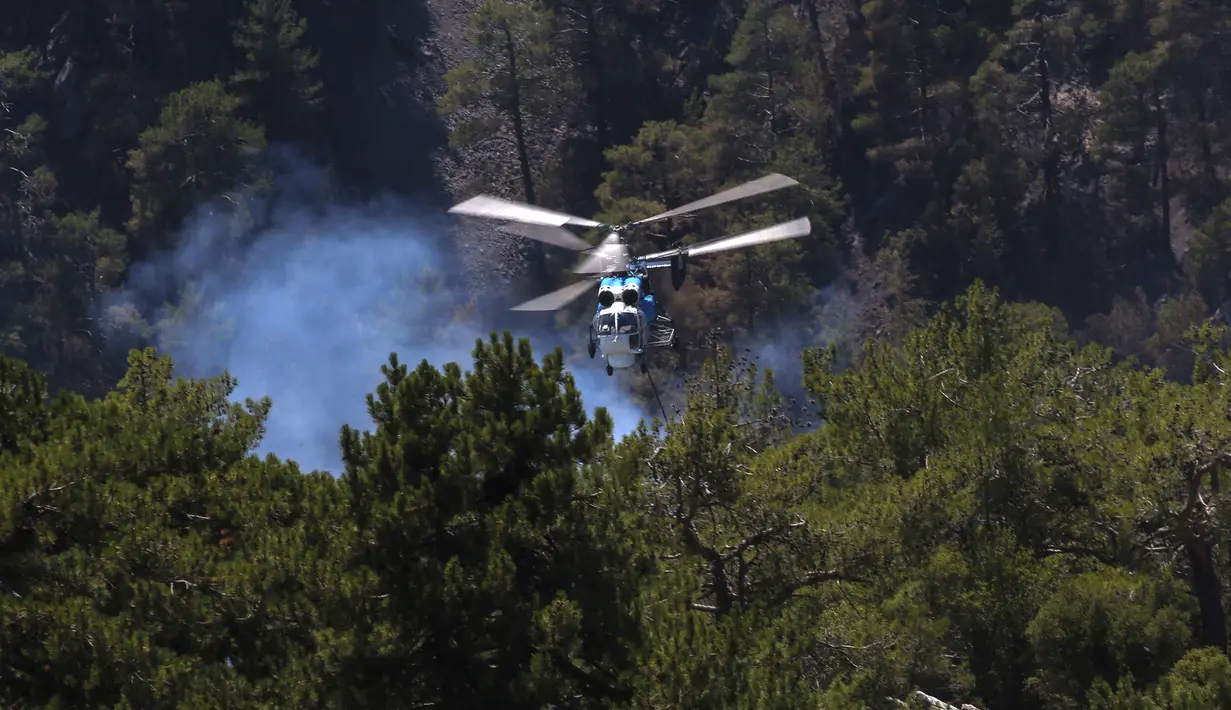 Sebuah helikopter berpartisipasi dalam operasi pemadaman kebakaran hutan di Koycegiz, Mugla, Turki, Senin (9/8/2021). Kebakaran hutan di Turki telah menewaskan delapan orang serta hewan yang tidak terhitung jumlanya. (AP Photo/Emre Tazegul)