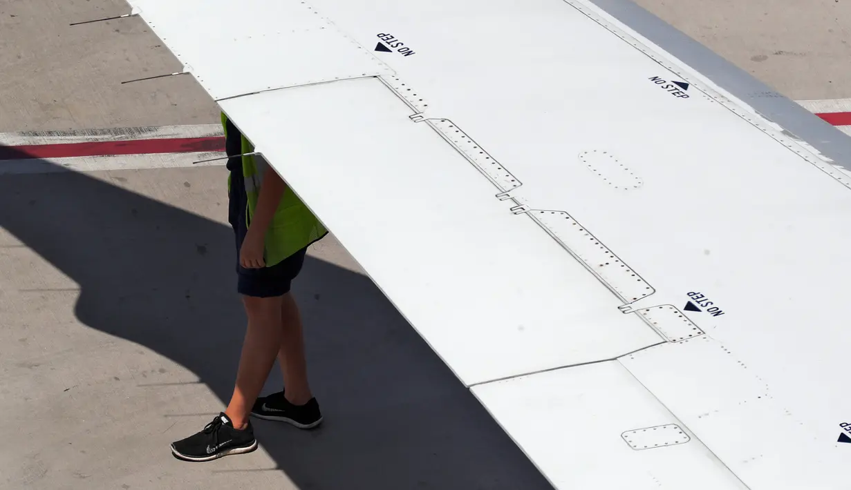 Kru American Airlines berlindung dari cuaca panas dengan berteduh di bawah sayap pesawat terbang di Bandara Internasional Sky Harbor, Phoenix, Amerika Serikat, Rabu (25/7). Phoenix mencapai rekor suhu tinggi pada Senin dan Rabu sore. (AP Photo/Matt York)