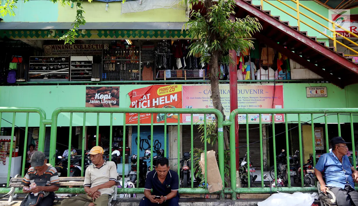 Sejumlah orang duduk dengan latar belakang Blok G Pasar Tanah Abang, Jakarta, Rabu (7/3). Sebelum dirobohkan, Pemprov DKI harus memastikan terlebih dulu relokasi pedagang di Blok G Pasar Tanah Abang sudah bisa dilakukan. (Liputan6.com/Johan Tallo)