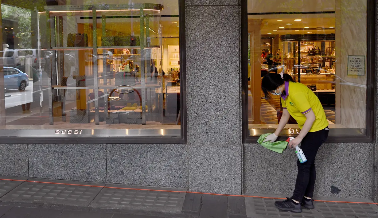 Seorang petugas kebersihan menyeka bagian depan toko Gucci di Melbourne, Kamis (28/10/2021). Toko-toko di kota ini bersiap untuk menyambut kembali pelanggan setelah menjalani penguncian pandemi keenam. (AFP/William West)