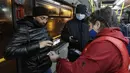 Seorang petugas memeriksa kode QR penumpang yang membuktikan tidak adanya infeksi virus corona pada layar ponsel pintar, di dalam bus di Kazan, Senin (22/11/2021). Kazan, menjadi yang pertama di Rusia yang mulai mewajibkan bukti vaksinasi sebelumnya untuk akses transportasi umum. (AP Photo)