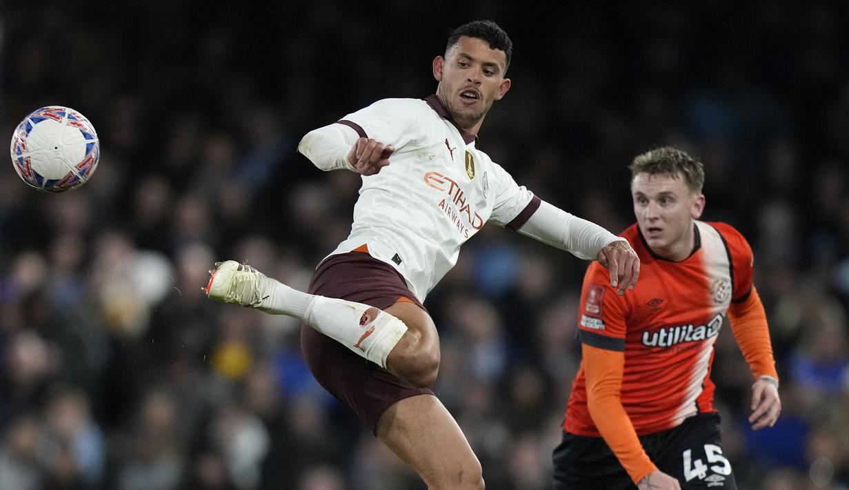 Gelandang Manchester City, Matheus Nunes (kiri) melepaskan umpan dengan tumitnya di depan Luton Town, Alfie Doughty pada laga putaran kelima Piala FA 2023/2024 di Kenilworth Road Stadium, Luton, Selasa (27/2/2024). (AP Photo/Alastair Grant)