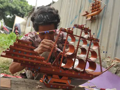 Perajin merekatkan miniatur perahu phinisi yang terbuat dari bambu, Jawa Barat, Sabtu (9/7). Perajin mengaku membanjirnya produk kerajinan dari China menyebabkan terhentinya ekspor dan penurunan permintaan dalam negeri. (Liputan6.com/Gempur M Surya)