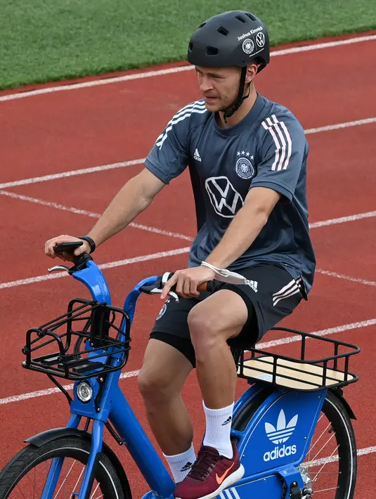 Gelandang Jerman, Joshua Kimmich tiba dengan sepeda sebelum sesi latihan menjelang UEFA EURO 2020 di World of Sports Campus di Herzogenaurac (11/6/2021). Jerman berada di grup F Euro 2020 bersama Portugal, Prancis dan Hungaria. (AFP/Christof Stache)