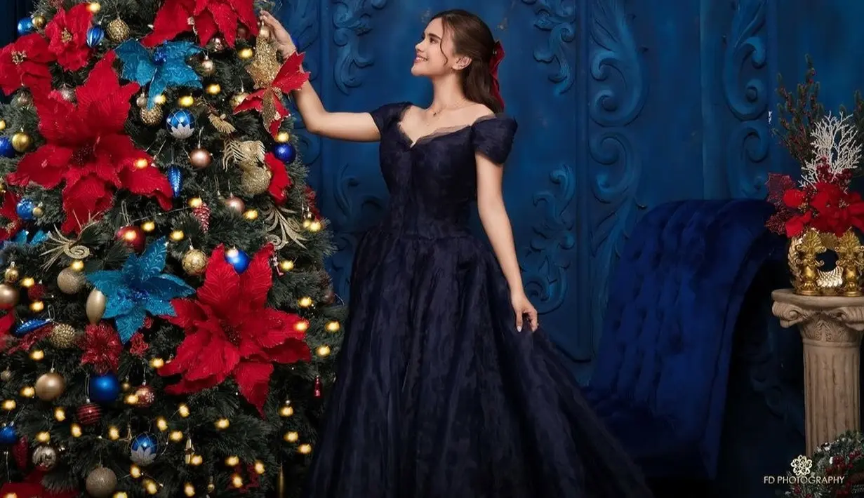 Terdapat beberapa potret Audi Marissa yang terlihat cantik saat mengenakan dress navy di dekat pohon natal