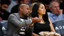 Petinju Floyd Mayweather Jr dan Jamie Lynn duduk di tepi lapangan saat menonton pertandingan NBA antara Los Angeles Lakers melawan Washington Wizards di Los Angeles (28/3). (AP Photo/Danny Moloshok)