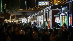 Sejumlah penumpang bersiap untuk naik kereta wisata yang dihiasi lampu Natal di Bogota (20/12/2019). Meyambut Hari Natal, kereta wisata di Kolombia membuat cara unik dengan memasangkan lampu warna-warni agar menjadi daya tarik penumpang. (AFP Photo/Juan Barreto)