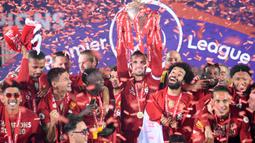 Gelandang Liverpool, Jordan Henderson, mengangkat trofi juara Premier league 2019-2020 di Stadion Anfield, Kamis (23/7/2020) dini hari WIB. Prosesi angkat trofi juara ini dilakukan usai pertandingan Liverpool melawan Chelsea. (AFP/Laurence Griffiths/pool)