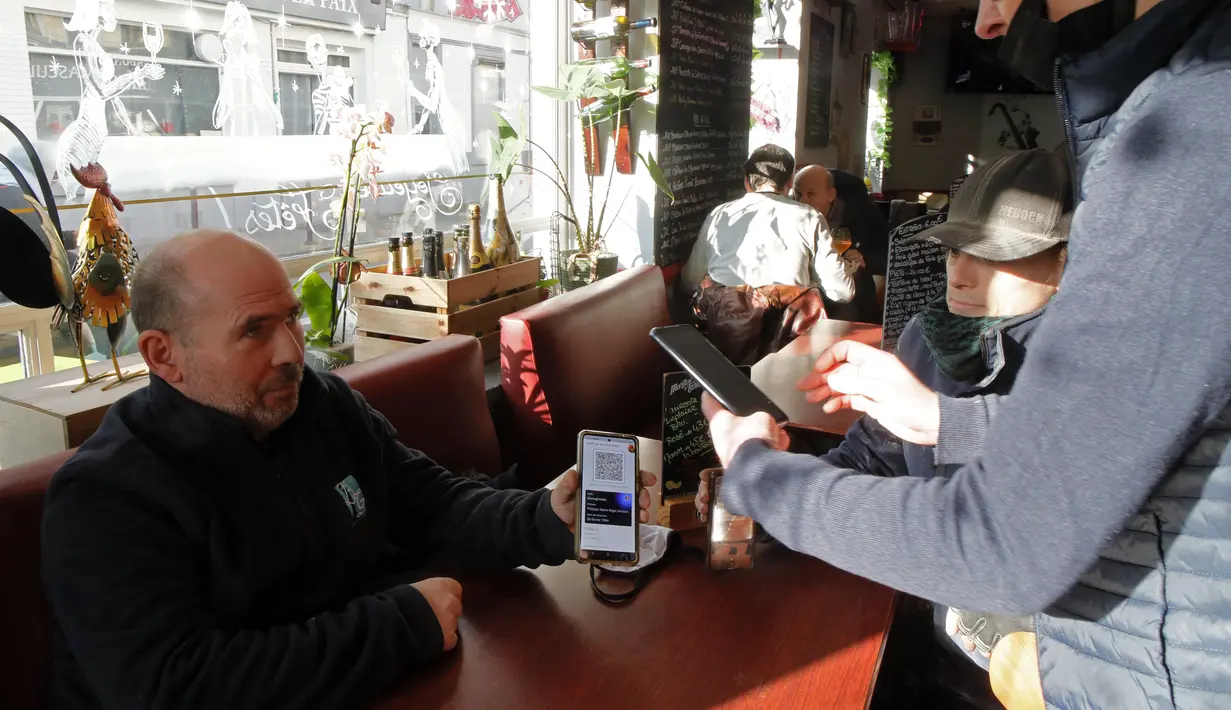 Pramusaji memeriksa kartu vaksin seorang pria di sebuah restoran di Lille, Prancis, Senin (24/1/2022). Orang yang tidak divaksinasi Covid-19 tidak lagi diizinkan di restoran, bar, lokasi wisata, dan tempat olahraga, kecuali mereka baru saja pulih dari infeksi virus tersebut. (AP Photo/Michel Spingle