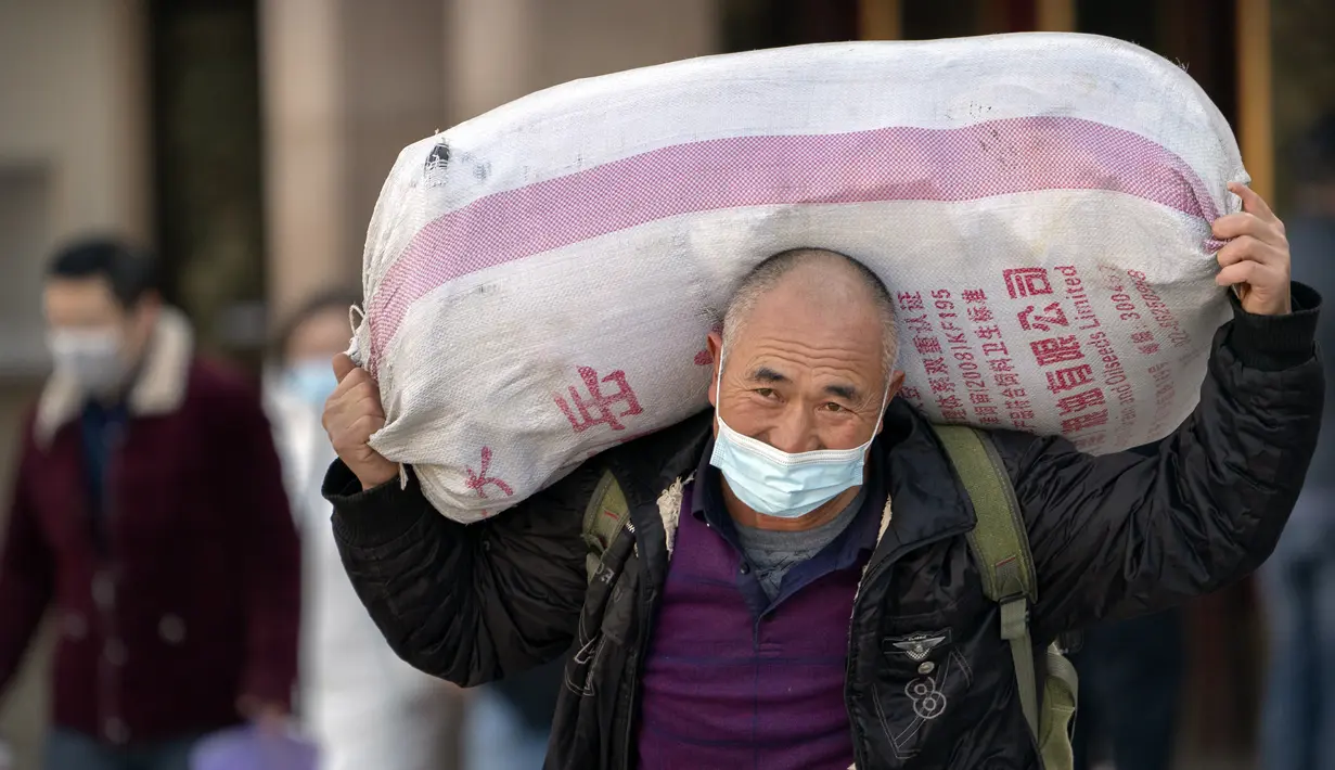 Seorang pelancong yang mengenakan masker untuk melindungi dari penyebaran virus corona membawa kopernya saat dia berjalan keluar dari pintu keluar di Stasiun Kereta Api Beijing di Beijing, Kamis (28/1/2021).  (AP Photo/Mark Schiefelbein)
