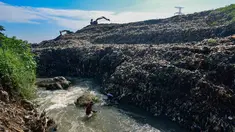 Warga memanfaatkan aliran Kali Pesanggrahan yang menyempit untuk mendulang benda-benda logam di kawasan Pasir Putih, Depok, Jawa Barat, Senin (27/4/2026), setelah longsoran sampah dari Tempat Pembuangan Akhir (TPA) Cipayung menutup sebagian badan sungai. (merdeka.com/Arie Basuki)