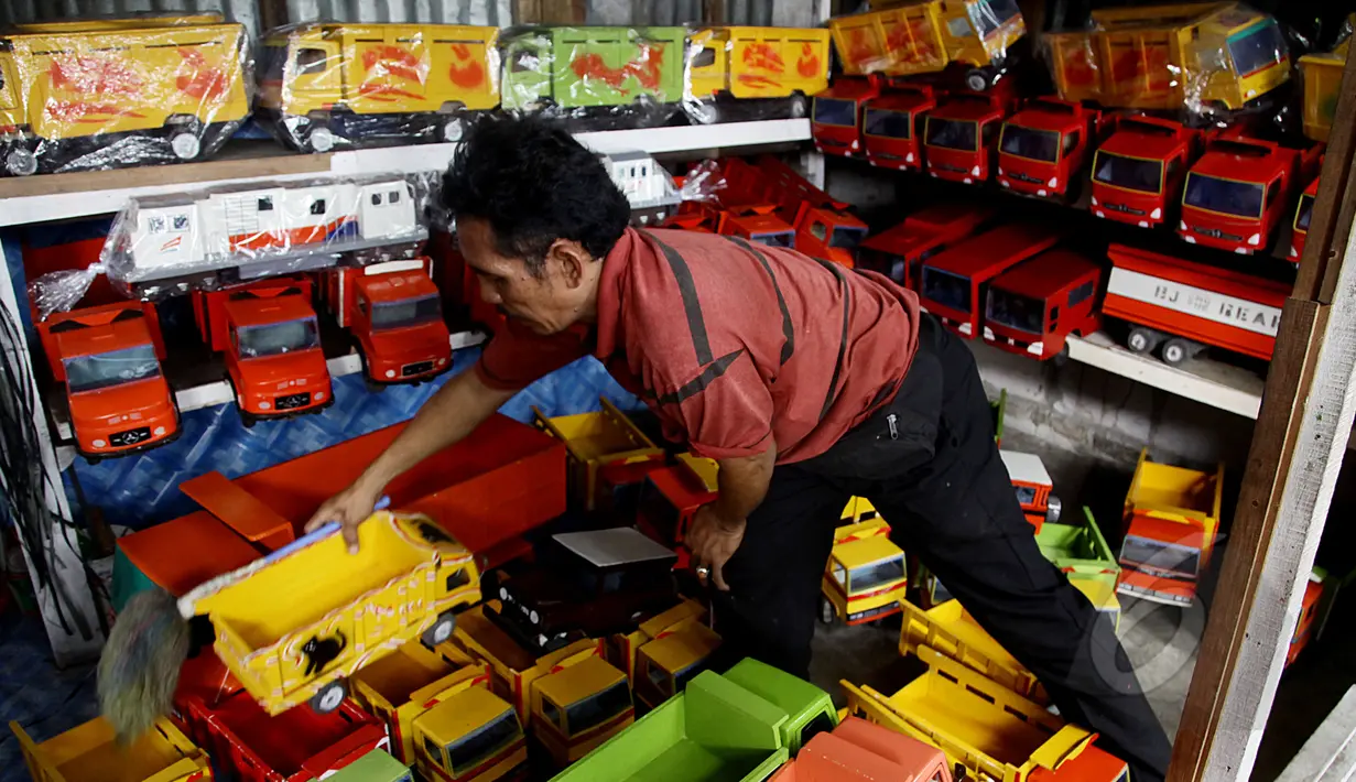 Pedagang mobil kayu merapihkan jualannya di kawasan Kalibata, Jakarta (27/5/2015). Produksi mainan lokal dan tradisional diharapkan mampu bertahan, mengingat pasar bebas Asean yang dimulai Januari 2016 mendatang. (Liputan6.com/Johan Tallo)