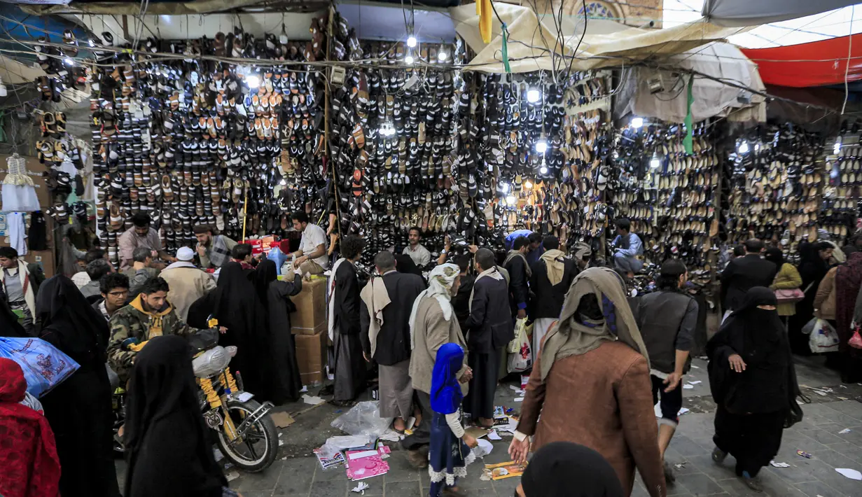 Orang-orang memilih sepatu dan sandal di pasar terbuka di ibu kota Yaman, Sanaa (2/5/2021). Umat Muslim di Yaman memenuhi pasar menjelang liburan Idul Fitri yang menandai akhir bulan suci Ramadhan. (AFP/Mohammed Huwais)