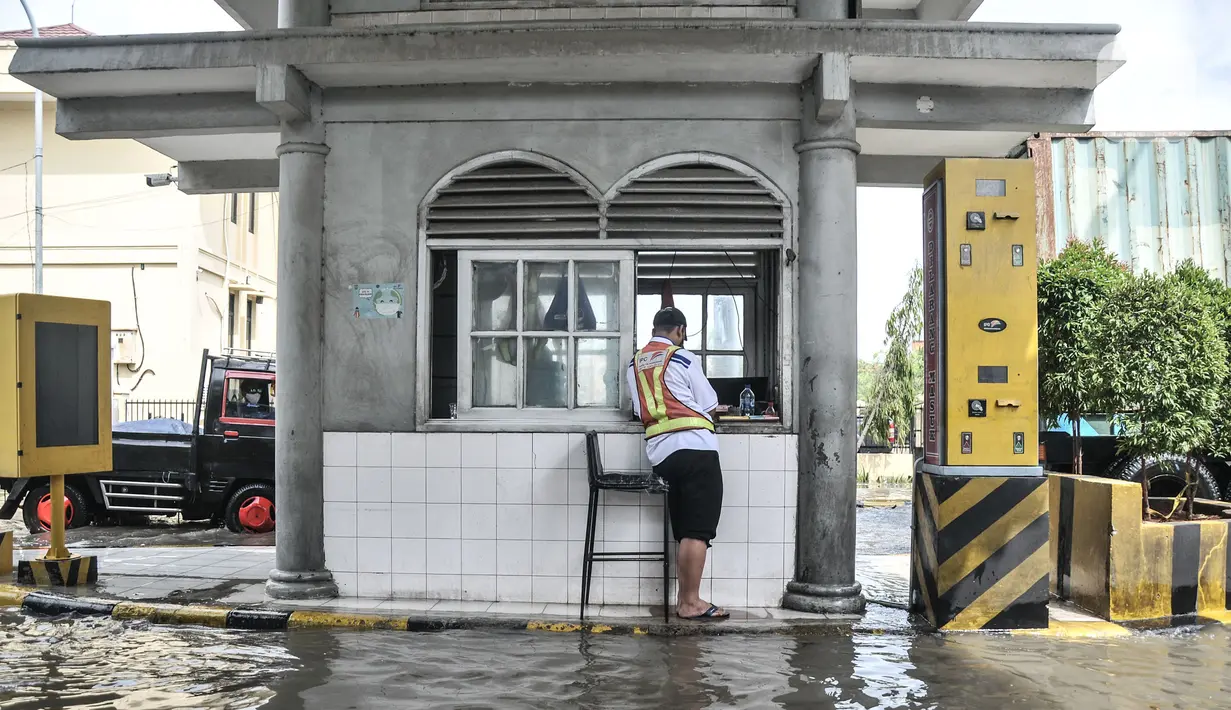 Petugas berjaga di pintu masuk saat banjir rob merendam Pelabuhan Sunda Kelapa, Jakarta, Senin (6/12/2021). Banjir rob kembali merendam kawasan Pelabuhan Sunda Kelapa sejak pagi tadi hingga ketinggian 70 cm dan menyebabkan terganggunya aktivitas bongkar muatan kapal. (merdeka.com/Iqbal S Nugroho)