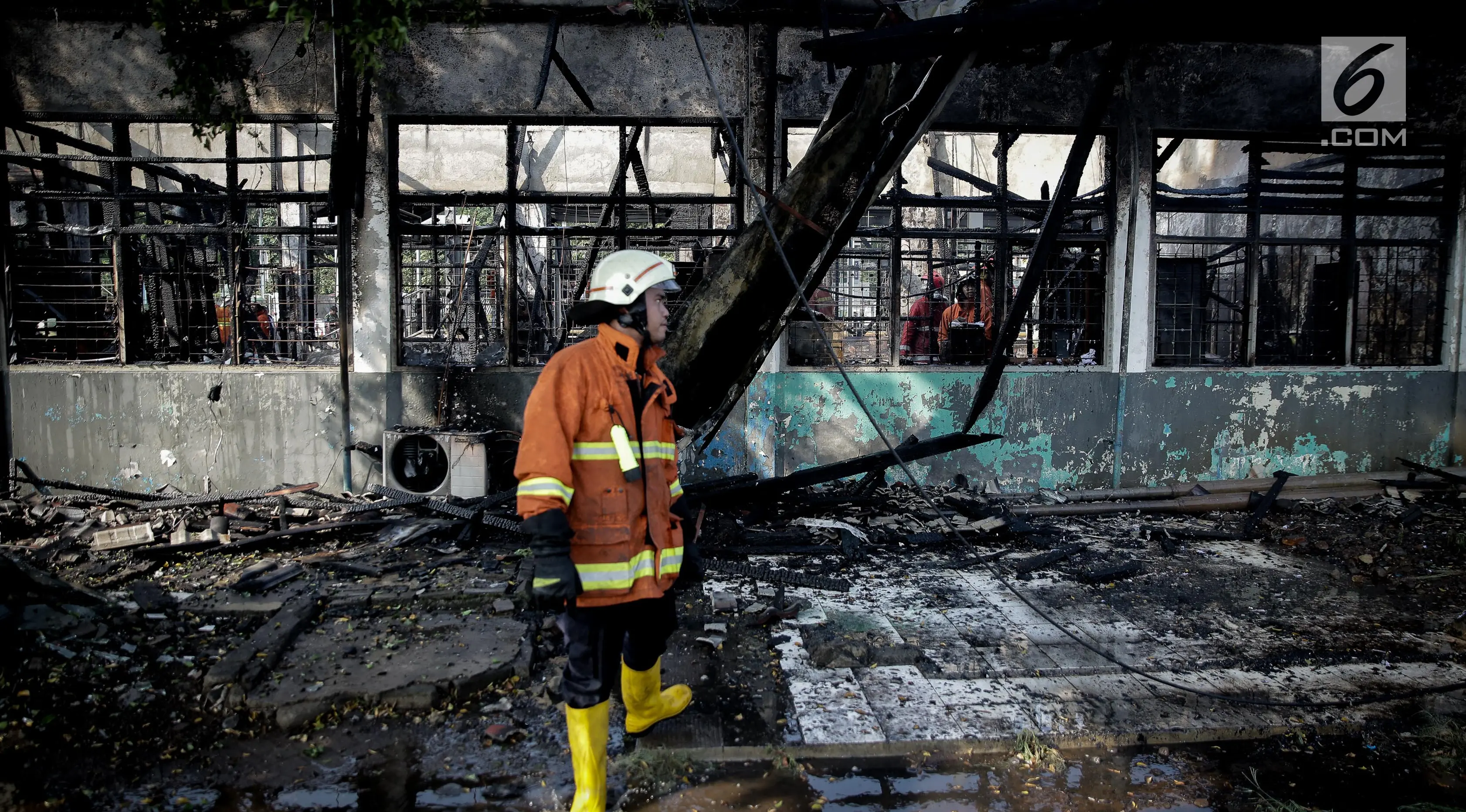 Petugas pemadam kebakaran mengamati sisa Stasiun Klender, Jakarta Timur yang terbakar, Jumat (19/5). Kebakaran yang terjadi sekitar 07.30 WIB di Stasiun Klender ini melalap kantor kepala stasiun hingga loket tiket. (Liputan6.com/Faizal Fanani)