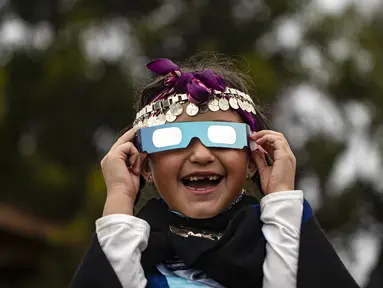 Magdalena Nahuelpan, seorang gadis Adat Mapuche, melihat gerhana matahari total menggunakan kacamata khusus di Carahue, La Araucania, Chile, Senin (14/12/2020). Gerhana matahari total terlihat dari Chile dan wilayah Patagonia utara Argentina. (AP Photo/Esteban Felix)