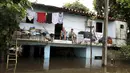 Sebuah keluarga duduk di atas rumah mereka akibat banjir melanda Asuncion, Paraguay, Senin (28/12). Banjir terparah dalam kurun waktu 23 tahun ini, bahkan telah membuat lebih dari 100.000 warga mengungsi. (REUTERS/Jorge Adorno)