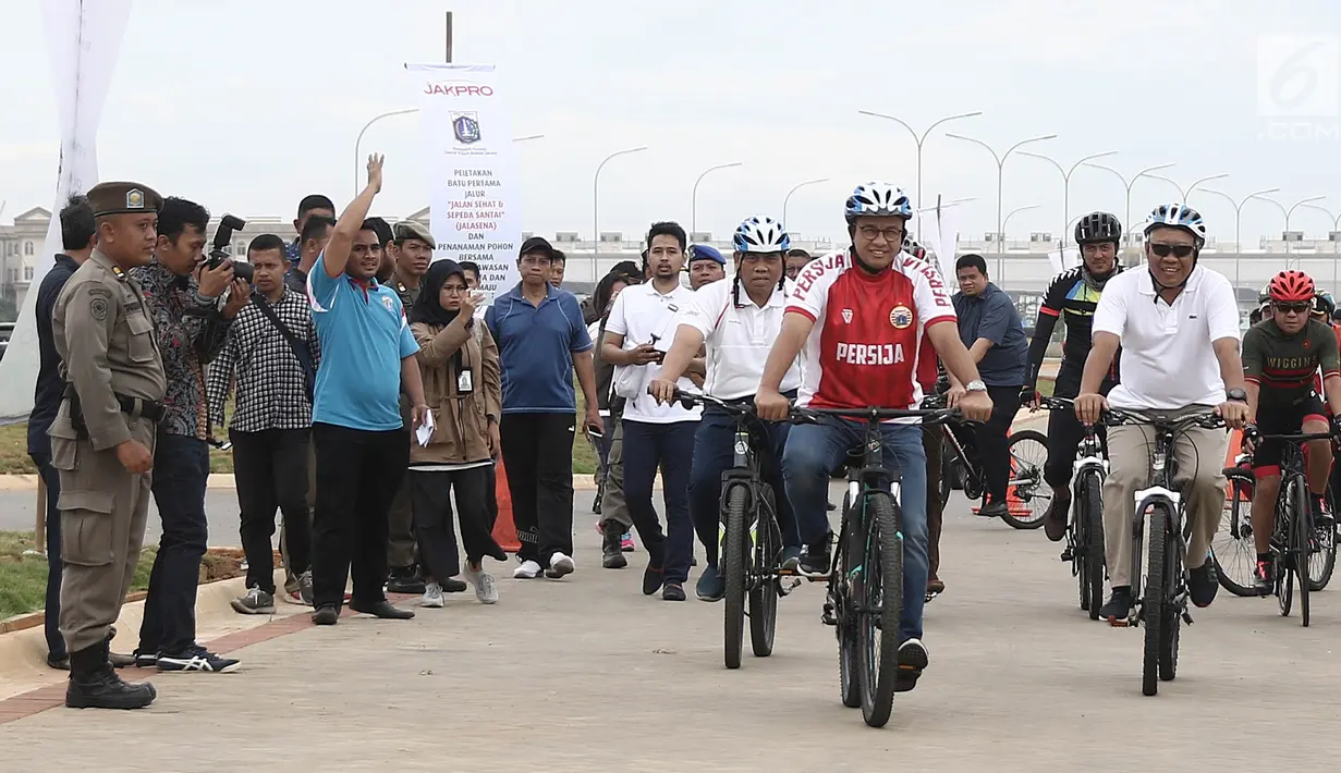 Gubernur DKI Jakarta Anies Baswedan bersepeda di kawasan Pantai Kita dan Pantai Maju, Minggu (23/12). Aksi itu mengawali Peletakkan Batu Pertama Jalur Jalan Sehat dan Sepeda Santai (Jalasena) di pulau reklamasi tersebut. (Liputan6.com/Herman Zakharia)
