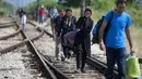 Imigran dengan membawa barang menyusuri rel kereta api saat perjalanan menuju Gevgelija, wilayah perbatasan Macedonia-Yunani, Kamis (9/7/2015). Mereka menempuh ribuan kilometer agar dapat mengejar kereta api tujuan Serbia. (AFP PHOTO/Robert ATANASOVSKI)