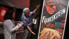 Kurator Daniel Finamore menjelaskan isi pameran ke salah satu wartawan di Museum Peabody Essex, Massachusetts, Rabu (9/8). Pameran poster film horor dan fiksi ilmiah ini koleksi pribadi milik gitaris band Metallica Kirk Hammet. (AP/Michael Dwyer)