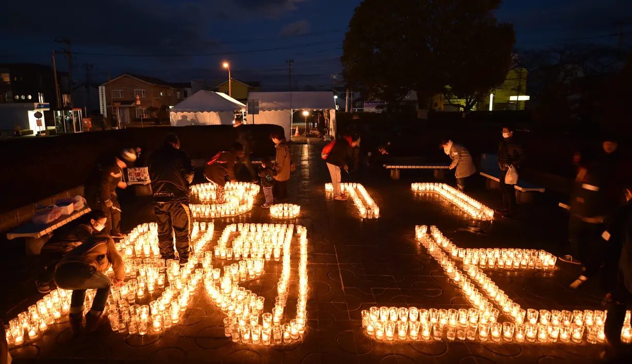 Pengunjung melihat lilin yang membentuk angka 3.11 dan nama kota Yuriage saat upacara peringatan bencana gempa tsunami yang terjadi pada tahun 2011 di Natori, Prefektur Miyagi, Jepang (11/3). (AFP/Kazuhiro Nogi)