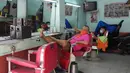 Tukang cukur menunggu pelanggan saat membuka kembali toko mereka setelah beberapa aktivitas bisnis diizinkan beroperasi kembali di Quezon, Filipina, Kamis (16/9/2021). Pemerintah memulai uji coba lockdown granular, di mana pembatasan ketat diterapkan untuk area yang lebih kecil. (AP/Aaron Favila)