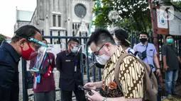 Seorang Jemaat memperlihatkan bukti pendaftaran untuk mengikuti ibadah di Gereja Katedral, Jakarta, Kamis (24/12/2020). 200 umat berada di dalam Gereja Katedral dan 109 umat berada di Plaza Maria. (Liputan6.com/Faizal Fanani)