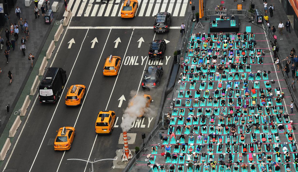 Sejumlah orang melakukan yoga bersama di kawasan Times Square, New York pada 'Summer Solstice' atau hari dengan siang terpanjang di musim panas, Rabu (21/6). Acara tersebut menandai Hari Yoga Internasional yang jatuh pada 21 Juni. (TIMOTHY A. CLARY/AFP)