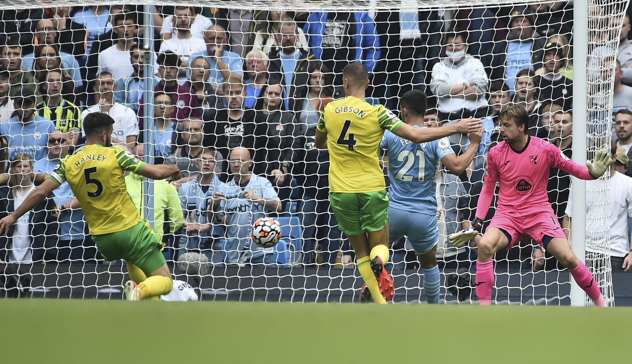 Manchester City sudah unggul 1-0 pada menit ke-7 usai kiper Norwich City, Tim Krul membuat gol bunuh diri. Aksinya yang berusaha menepis bola tendangan Gabriel Jesus yang sempat diblok kapten Norwich, Grant Hanley, justru menciptakan gol bunuh diri. (Foto: AP/Rui Vieira)