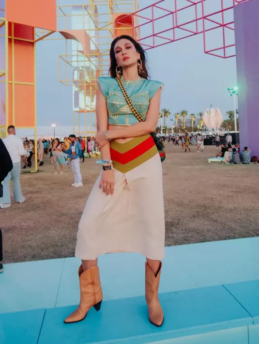 <p>Kembali berpose di acara Coachella, Luna Maya terlihat mengenakan crop top bersiluet busana India dengan motif dan detail payet di bagian depan. Ia padukan menggunakan mini skirt dengan detail apik di bagian pinggang dan boots berwarna netral. Foto: Instagram.</p>